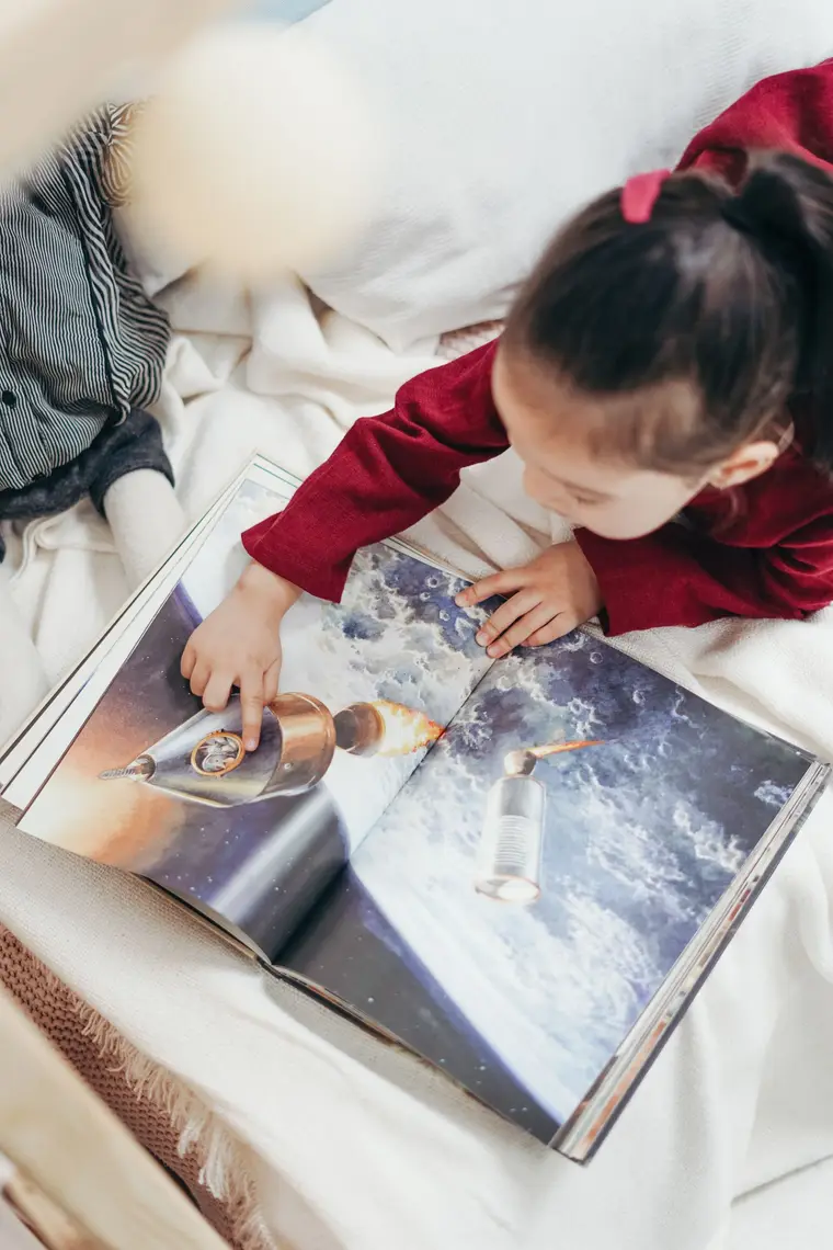 Niña explorando un libro ilustrado del espacio