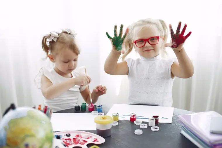 Niñas pequeñas con las manos pintadas de colores