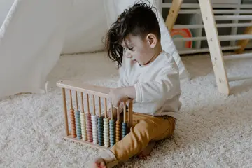 Niño pequeño aprendiendo con un ábaco de madera