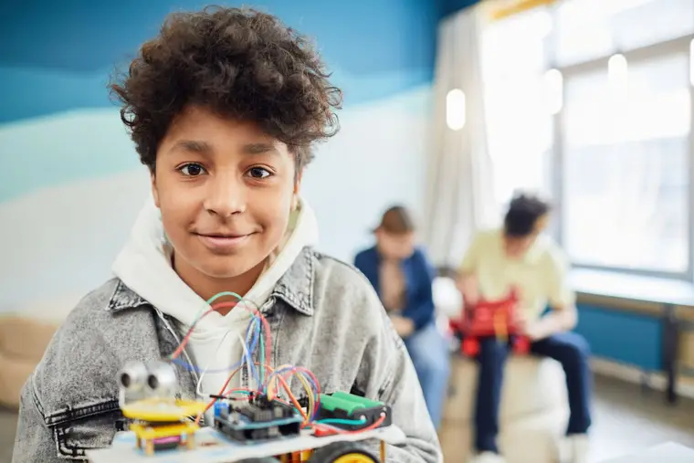 Niño sonriente con su proyecto de robótica