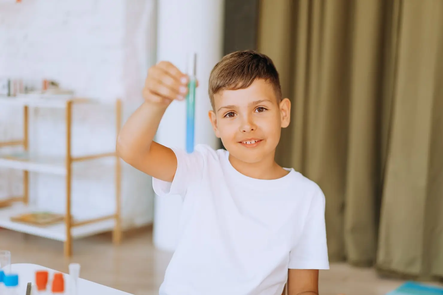 Niño sonriente sosteniendo un tubo de ensayo durante un experimento